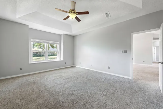 an empty room with a ceiling fan and windows