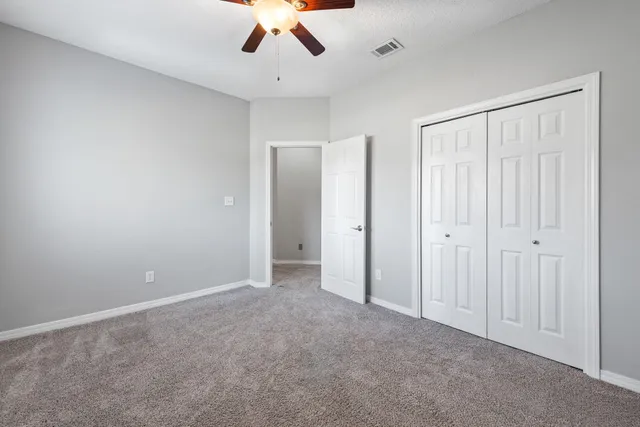a view of an empty room and chandelier fan