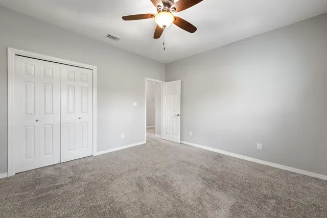 a view of an empty room and chandelier fan