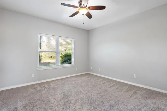 an empty room with a window and a fan