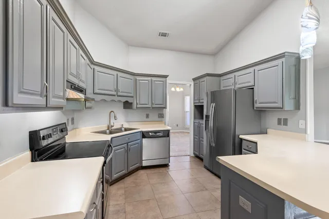 a kitchen with stainless steel appliances granite countertop a refrigerator stove top oven a sink and dishwasher