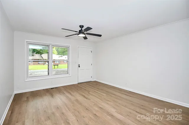 an empty room with a window and a ceiling fan