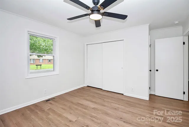a view of empty room with wooden floor and fan