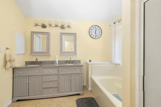 a spacious bathroom with a granite countertop sink mirror and bathtub