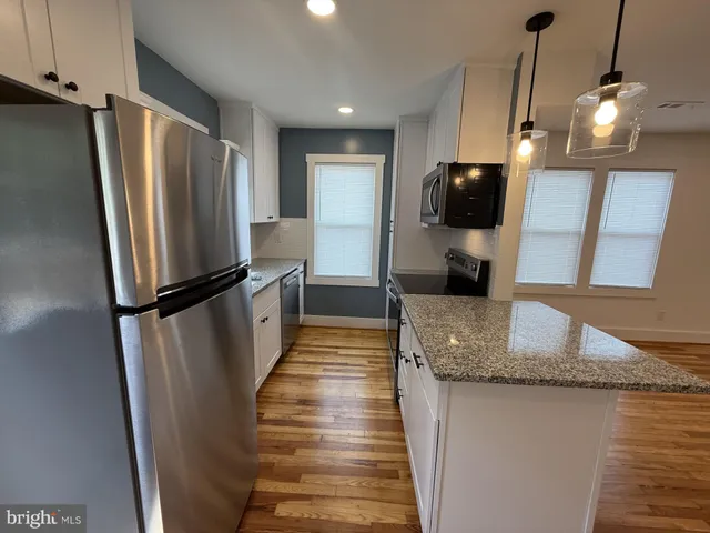 a kitchen with stainless steel appliances granite countertop a refrigerator a sink a stove and a refrigerator