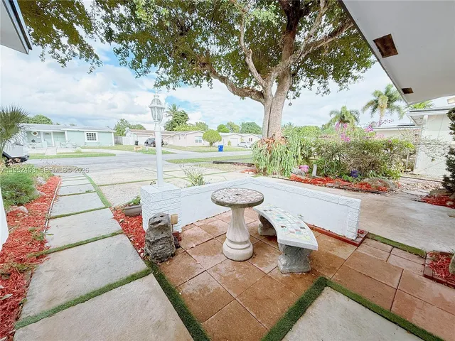 a view of a patio with table and chairs potted plants and a large tree