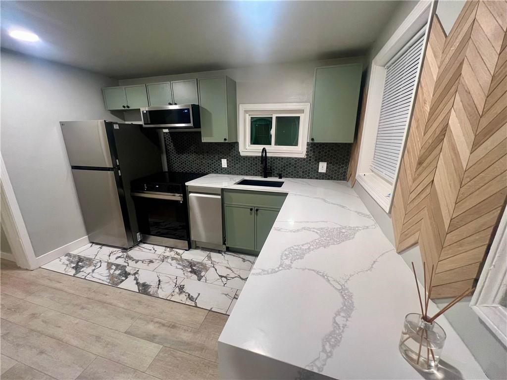 a living room with stainless steel appliances furniture a rug and a kitchen view