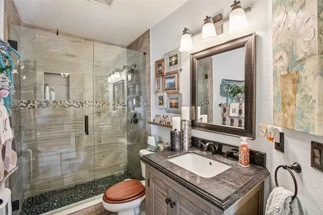 a bathroom with a granite countertop sink toilet a mirror a vanity and shower