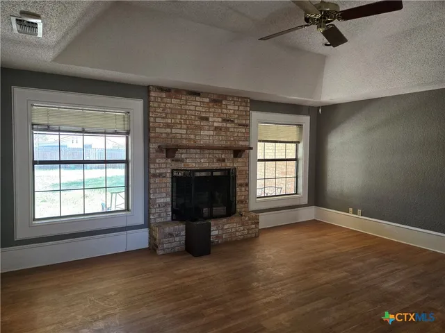 an empty room with windows and fireplace