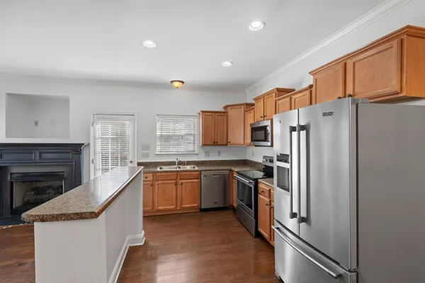 a kitchen with stainless steel appliances granite countertop a refrigerator a stove and a sink