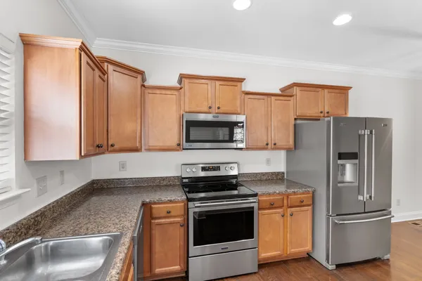 a kitchen with stainless steel appliances granite countertop a refrigerator stove and sink