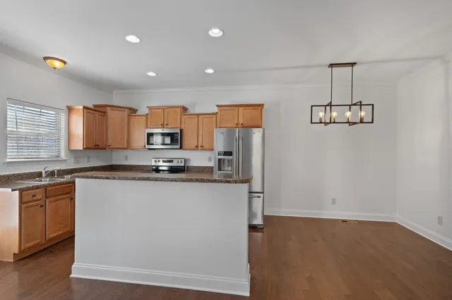 a large kitchen with stainless steel appliances a large counter top a stove a chimney a refrigerator and a sink