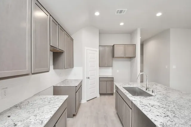 a kitchen with kitchen island granite countertop a sink and refrigerator