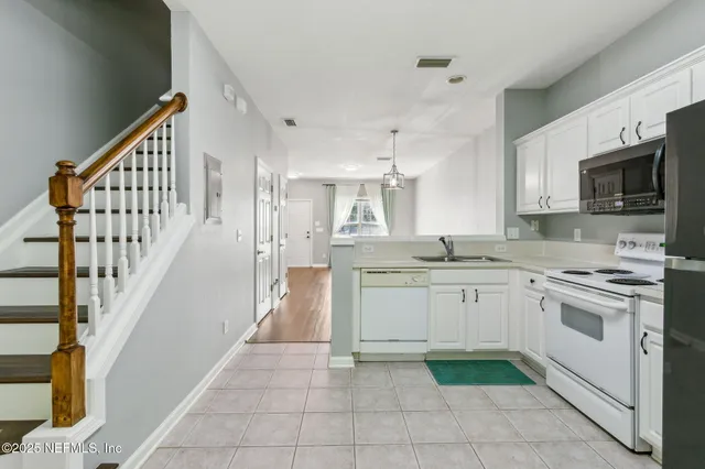 a kitchen with white cabinets and sink