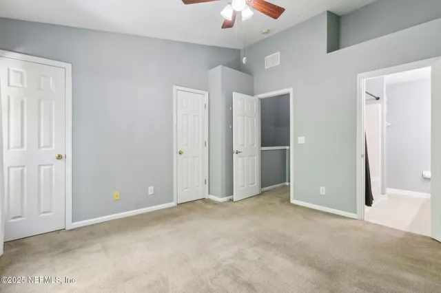 an empty room with closet and a chandelier fan