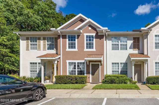 a front view of a residential houses with yard and green space