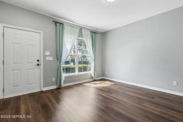 a view of an empty room with wooden floor and a window