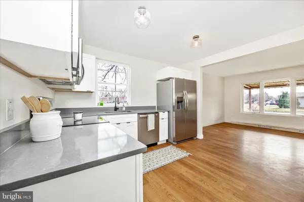 a kitchen with stainless steel appliances granite countertop a refrigerator a sink and white cabinets