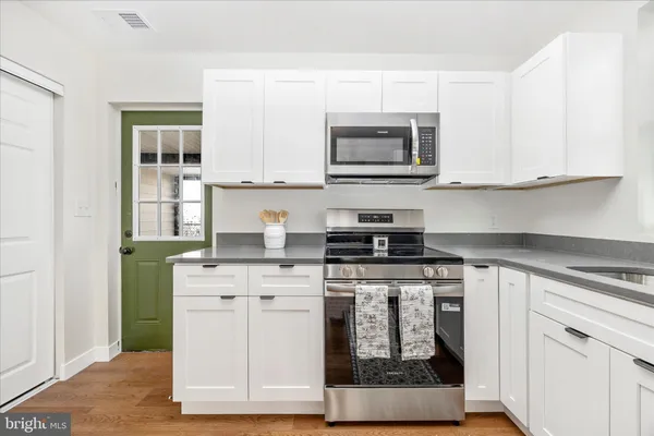 a kitchen with stainless steel appliances granite countertop a stove a microwave and a white cabinets