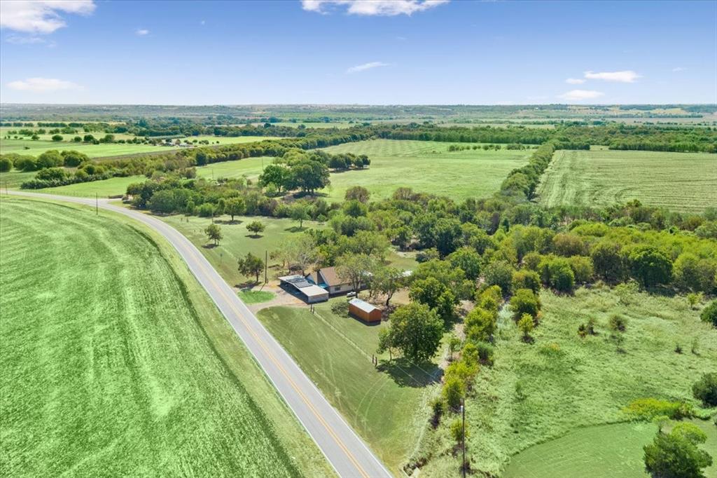 4246 Old Caufield Ranch Road McGregor, TX 76657 - Photo 1 of 31 Expansive green fields, mature trees, a long paved road, and a single-story residence