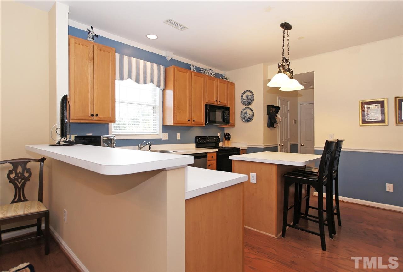 113 Inkster Cove Raleigh, NC 27603 - Photo 8 of 24 a kitchen with stainless steel appliances granite countertop a stove a sink a microwave a dining table and chairs with wooden floor