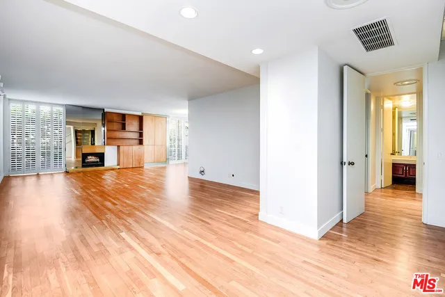 a view of a livingroom with wooden floor and a refrigerator