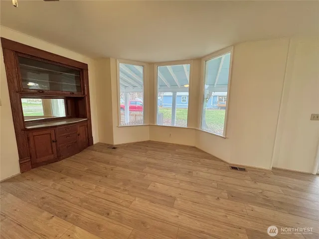 a view of an empty room with glass door and wooden floor