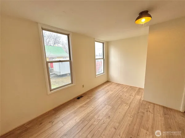 an empty room with wooden floor and windows