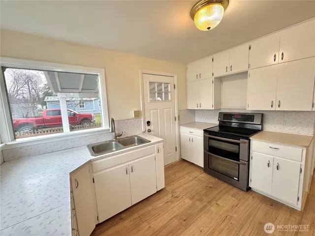 a kitchen with a sink stove and wooden floor