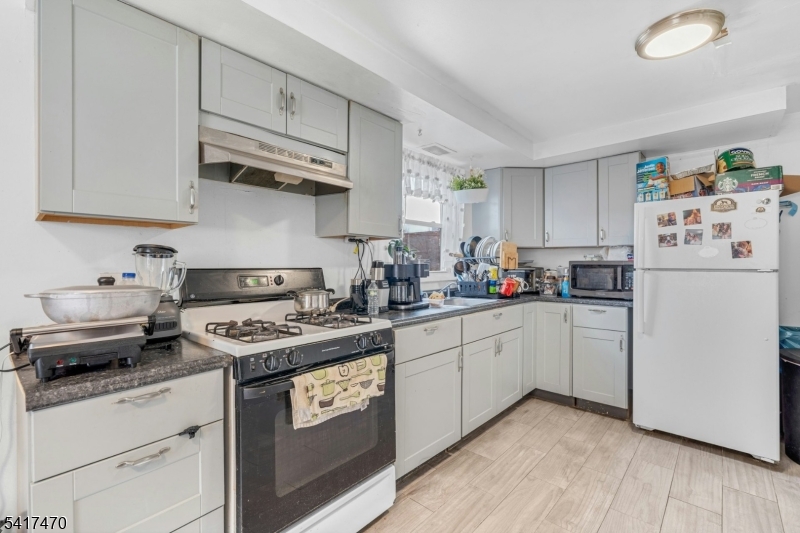 13 Allen Street Passaic, NJ 07055 - Photo 5 of 7 a kitchen with stainless steel appliances granite countertop a refrigerator a stove a sink and white cabinets