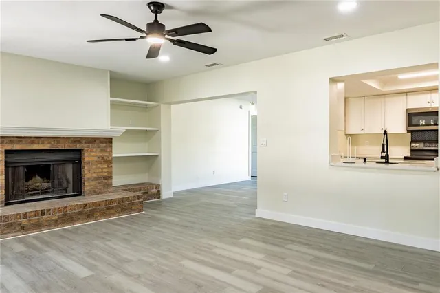 an empty room with wooden floor fireplace and windows
