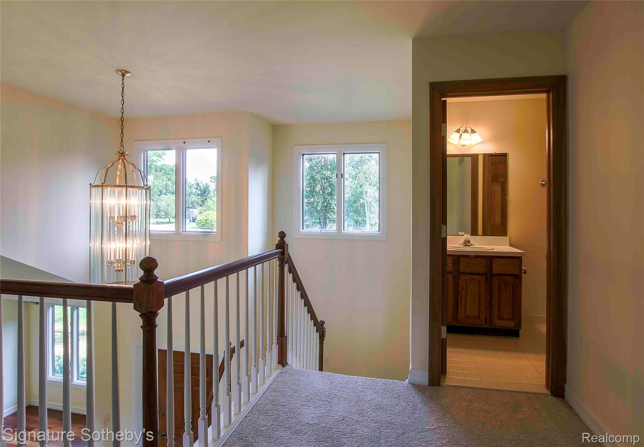 3131 Smugglers Ridge Walled Lake, MI 48390 - Photo 25 of 35 Second-story landing featuring a staircase with wood newel post and balusters, and multiple windows