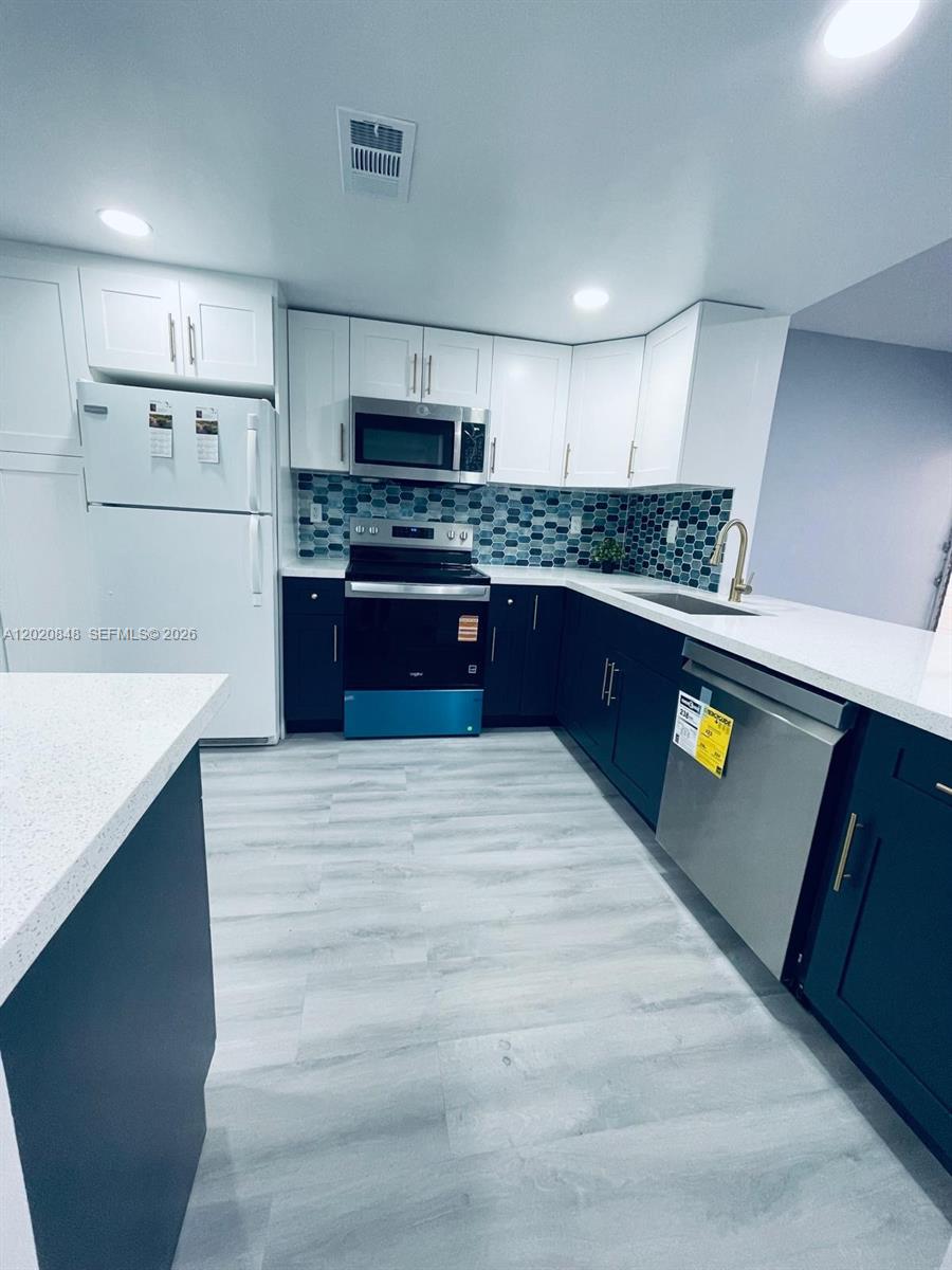 9175 Southwest 77th Avenue, Unit 306 Miami, FL 33156 - Photo 6 of 16 a large kitchen with stainless steel appliances granite countertop a stove a refrigerator a sink dishwasher and white cabinets with wooden floor