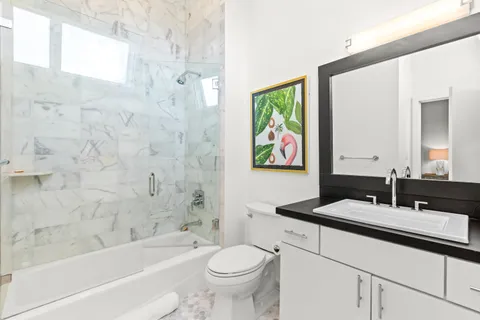 a bathroom with a granite countertop sink a toilet a mirror a bathtub and shower