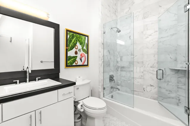 a bathroom with a granite countertop sink a toilet a mirror a bathtub and shower