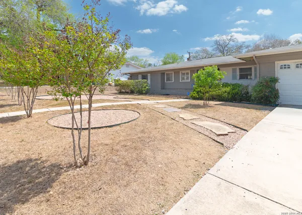 a front view of a house with a yard and trees