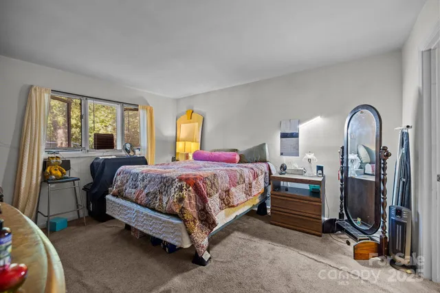 a spacious bedroom with a bed a mirror and windows