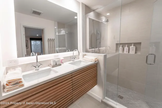 a bathroom with a double vanity sink mirror and shower