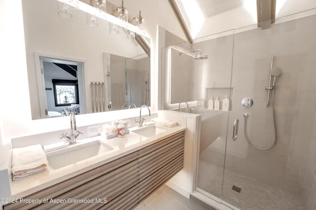 a bathroom with a granite countertop sink a mirror and a shower