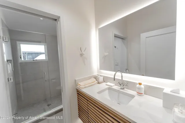 a bathroom with a granite countertop sink a mirror and shower