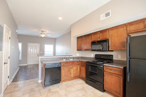 a kitchen with stainless steel appliances granite countertop a stove top oven a sink dishwasher a refrigerator and a dining table with wooden floor