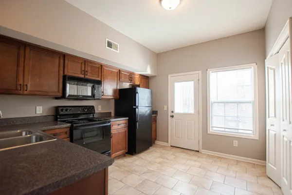 a kitchen with stainless steel appliances granite countertop a stove top oven a sink dishwasher and a refrigerator