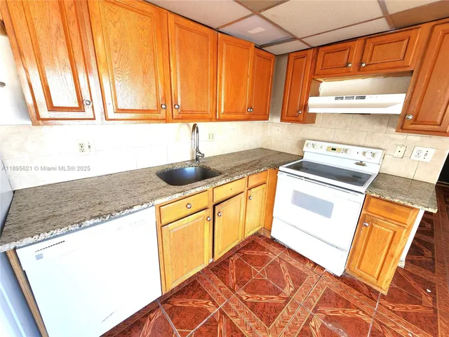 a kitchen with a sink a stove a refrigerator and cabinets