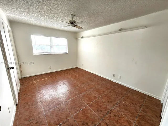 a view of a big room with wooden floor and chandelier fan
