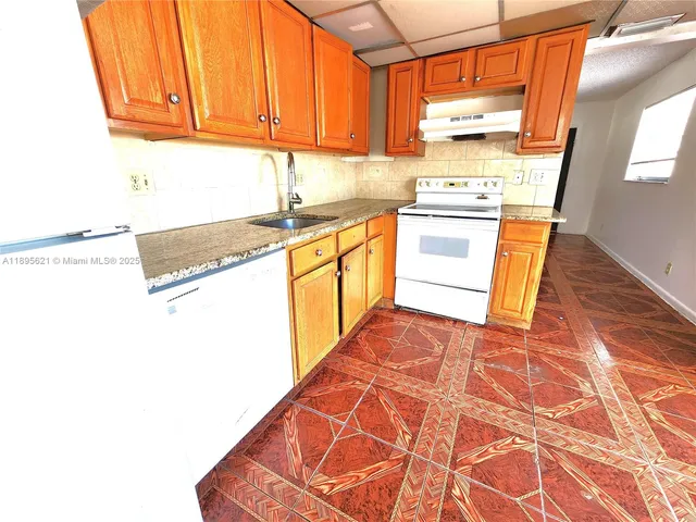 a kitchen with granite countertop cabinets stainless steel appliances a sink and a window