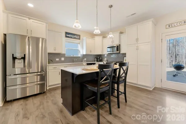 a kitchen with stainless steel appliances a refrigerator a sink a stove a dining table and chairs