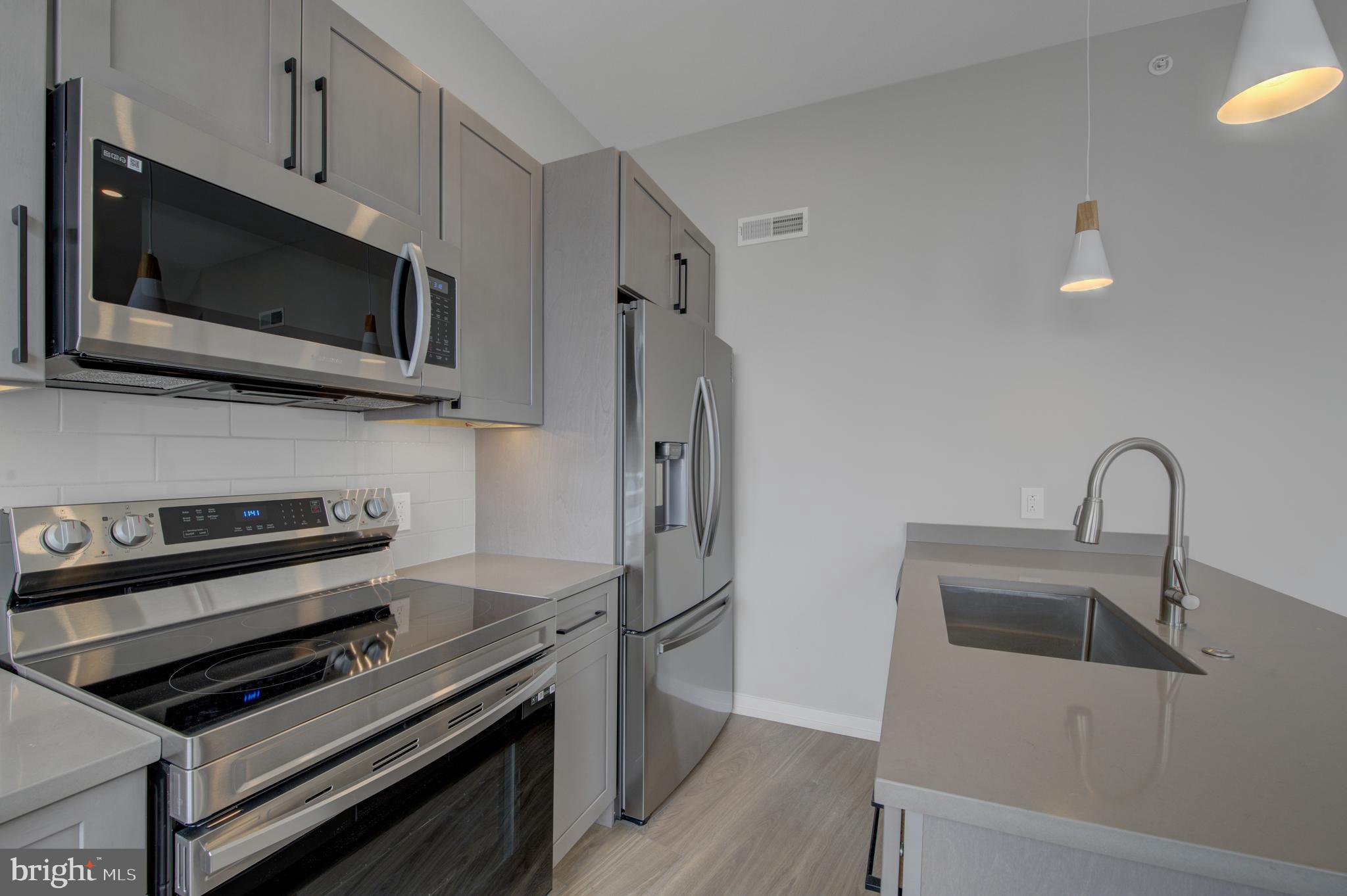 2445 Innovator Way, Unit 3A Philadelphia, PA 19146 - Photo 6 of 17 a kitchen with stainless steel appliances and wooden floor
