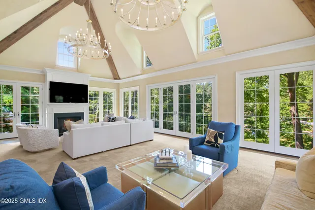 a living room with furniture large windows and flat screen tv