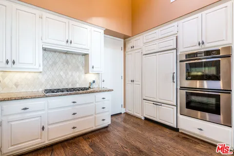 a kitchen with granite countertop white cabinets and stainless steel appliances