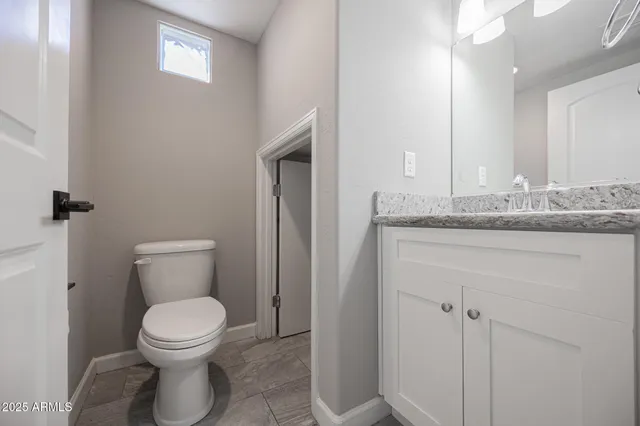a bathroom with a granite countertop toilet and a sink